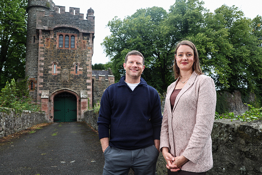 Two people standing in front of a castle.