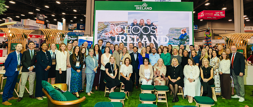 body-IRELAND TARGETS BUSINESS EVENTS GROWTH AT IMEX AMERICA Group photo of tourism industry representatives at the Meet in Ireland stand at a trade exhibition, in front of a large “Choose Ireland” display.