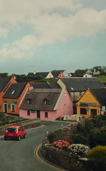Red car driving into colourful country village.