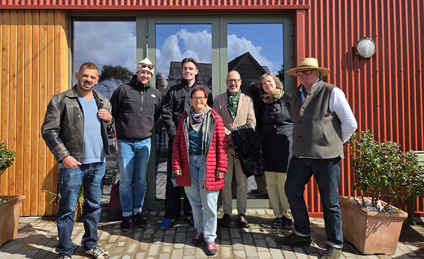 Group of people standing outside a modern wooden building entrance on a sunny day