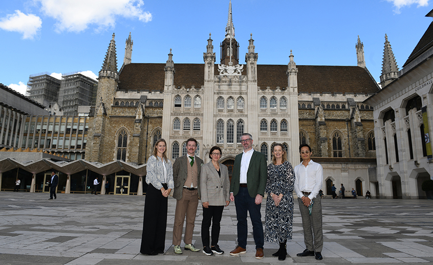 Group of six people standing in front of the historic Guildhall building in London.