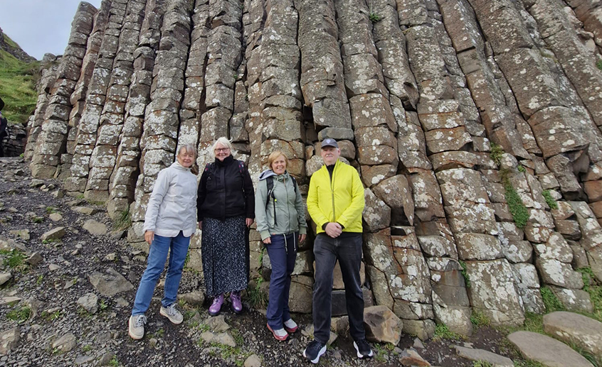 Four visitors stand beside towering basalt columns at the Giant’s Causeway, Northern Ireland.