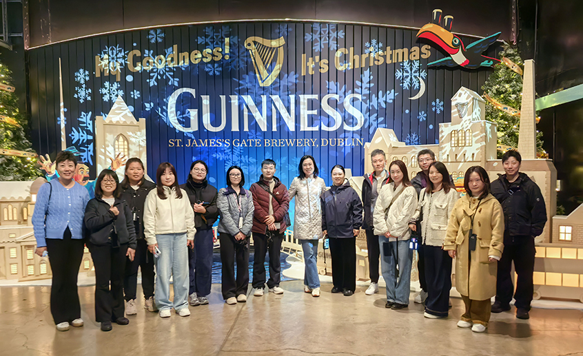 Group of people standing indoors at the Guinness St. James’s Gate Brewery in Dublin, with festive Christmas decorations and a large Guinness sign in the background.