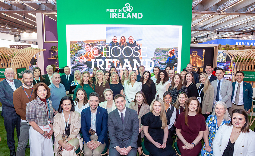 Group of delegates posing at a trade show stand featuring “Meet in Ireland” and “Choose Ireland” branding.