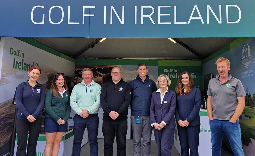 A group of people standing beneath a large 'Gold in Ireland' sign at an event.
