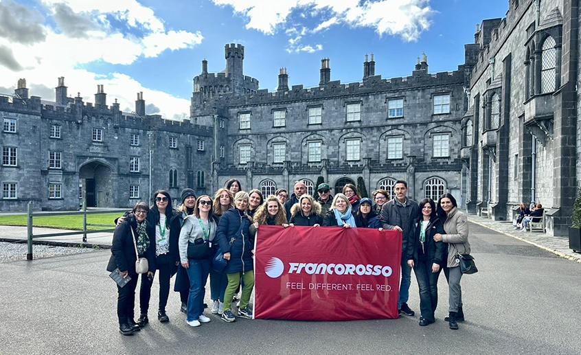 Group of travel agents holding a Francorosso banner in a historic stone courtyard in Ireland.