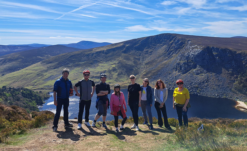 Group on a hilltop overlooking a lake and mountains.
