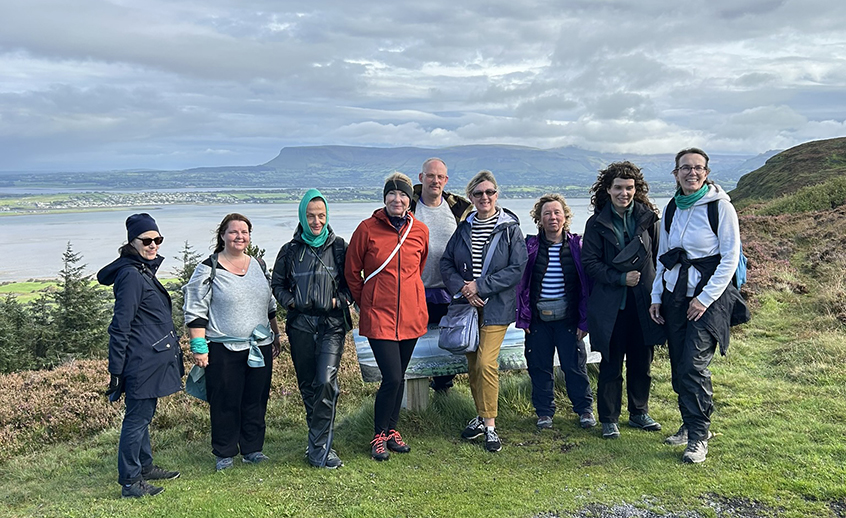 Group of people posing on a walking trail on a mountain beside the sea.