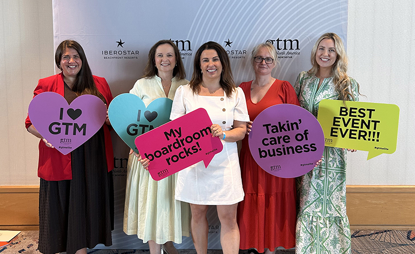 Five tourism representatives at a GTM North America event, holding colourful speech-bubble signs promoting Ireland.