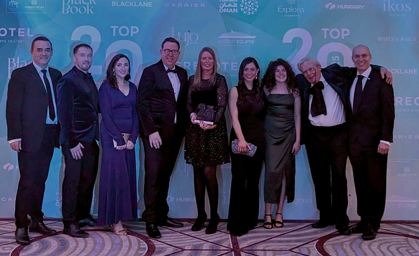 Group shot of nine people standing in front of a blue backdrop
