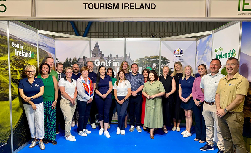 Group of people posing together at a golf tourism exhibition stand with “Golf in Ireland” branding