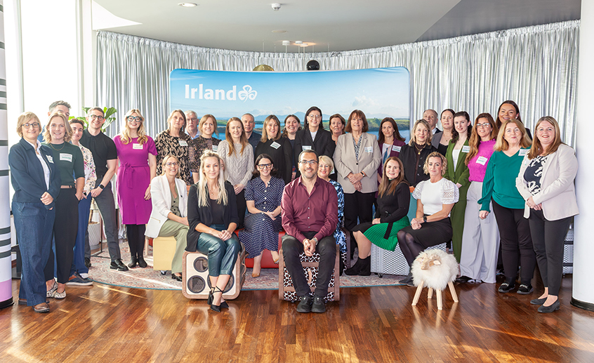 Group of people posing together at a Tourism Ireland B2B workshop, with an ‘Irland’ banner in the background.