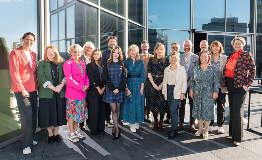 A group of people standing outdoors outside an event venue.