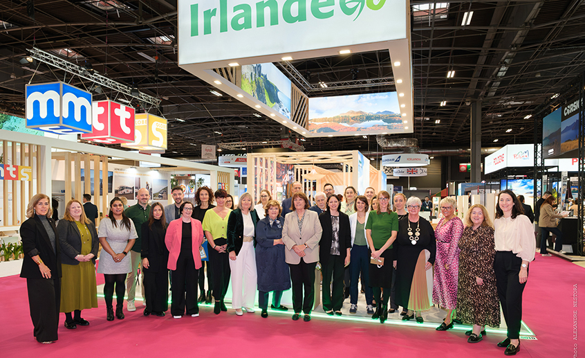 A large group of people posing indoors at the event in Paris underneath a green 'Irlande' sign.