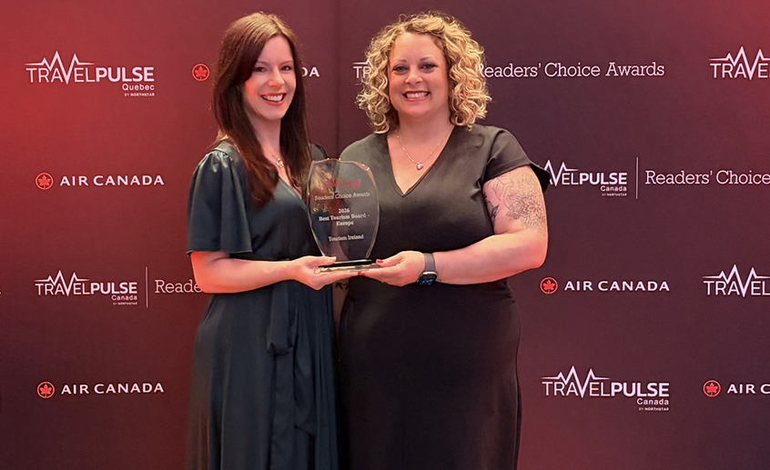 Two people holding an award plaque at the TravelPulse Readers’ Choice Awards with Air Canada branding in the background.