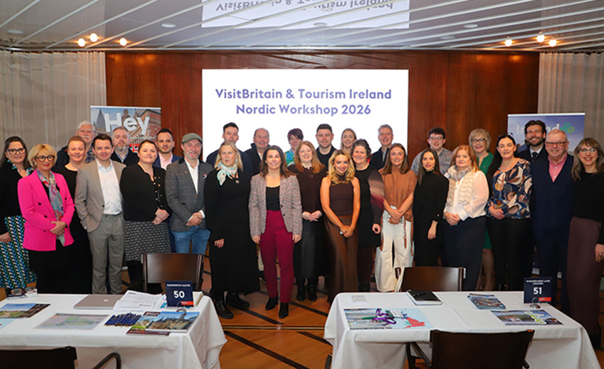 Group photo of participants standing together at the VisitBritain & Tourism Ireland Nordic Workshop 2026, with event tables and promotional banners visible.