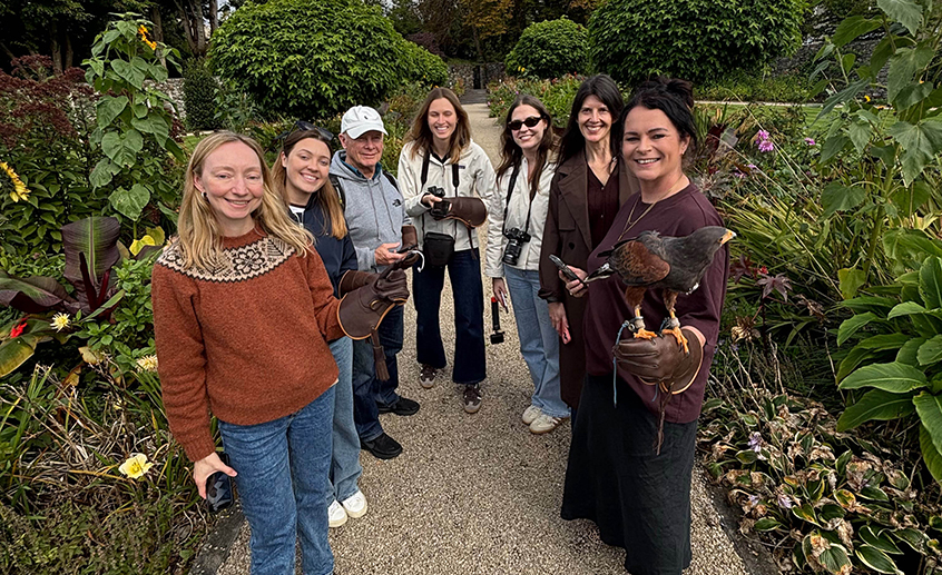Group of visitors holding birds of prey in a landscaped garden during a wildlife experience.