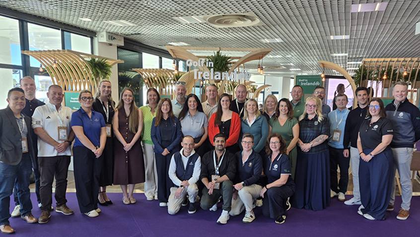 Group of delegates posing at the International Golf Travel Market in front of a Golf in Ireland display.