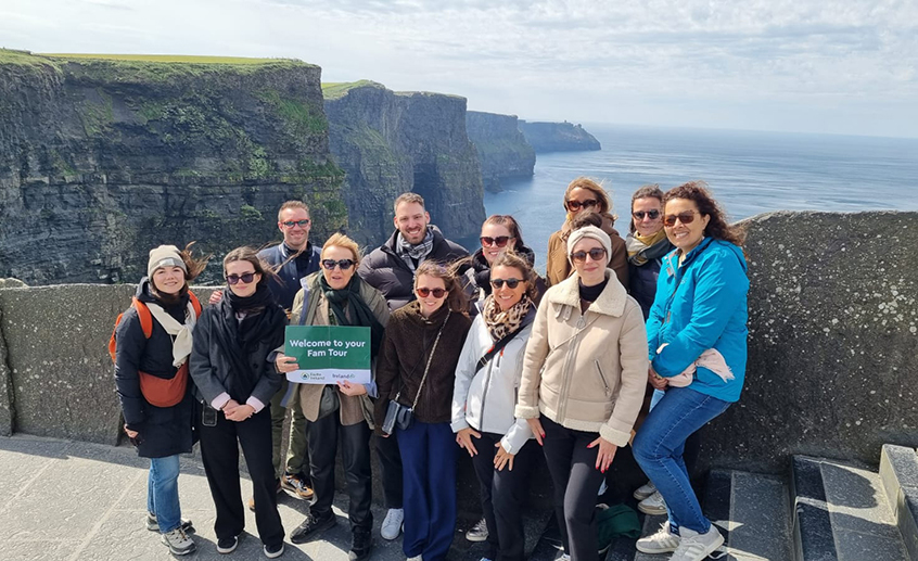 Travel agents at the Cliffs of Moher holding a “Welcome to your Fam Tour” sign