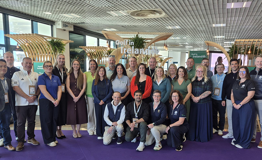 Group of delegates posing at the International Golf Travel Market in front of a Golf in Ireland display.
