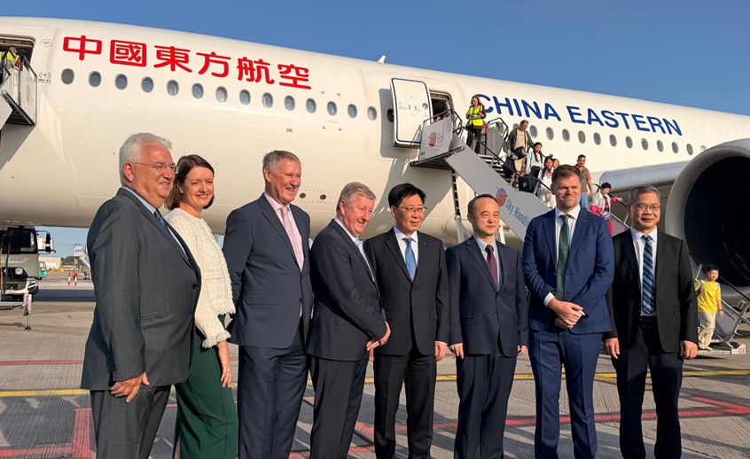 8 people standing in front of a China Eastern airplane on the runway.