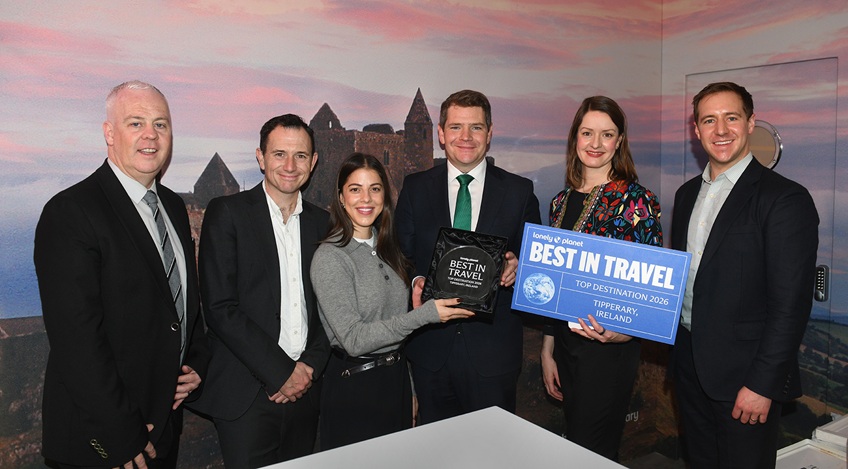 Six people at World Travel Market event holding a 'Best in Travel' sign in front of an Ireland stand with a picture of a castle on it.