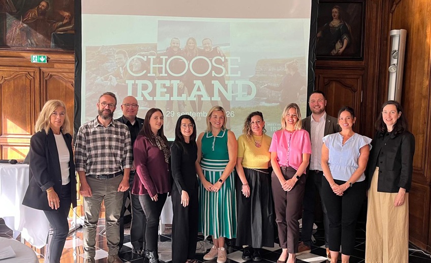 Group of people at a business event, standing in front of a presentation screen.