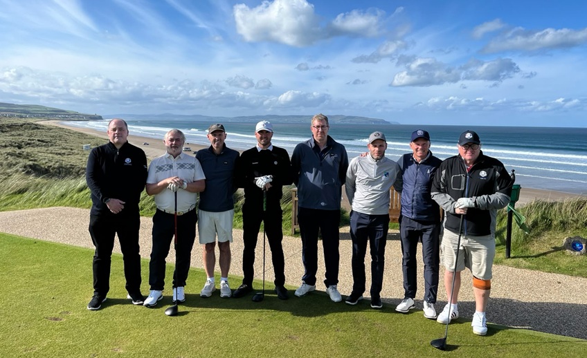 Golfers on a seaside tee overlooking the beach.