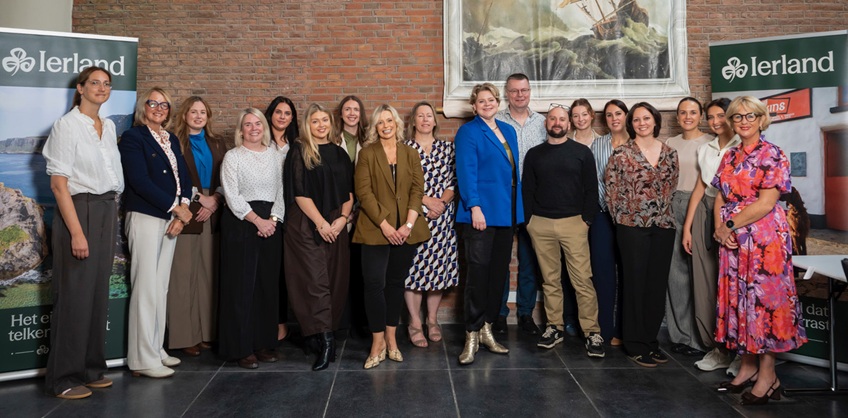 Large group of people of workshop attendees standing together in front of a red brick wall. 