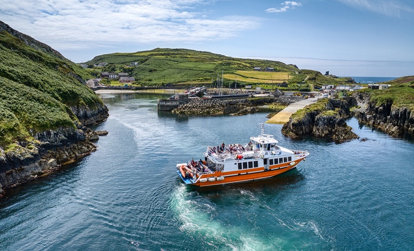 Orange ferry entering island harbour.