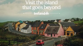 Picture of red car driving into colourful village with text saying 'Visit the island that goes beyond, Ireland'