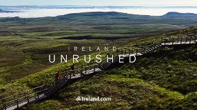 Boardwalk with 3 walkers in centre of scenic hill.
