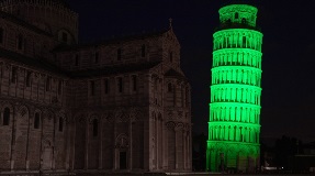 Leaning tower illuminated in green light.