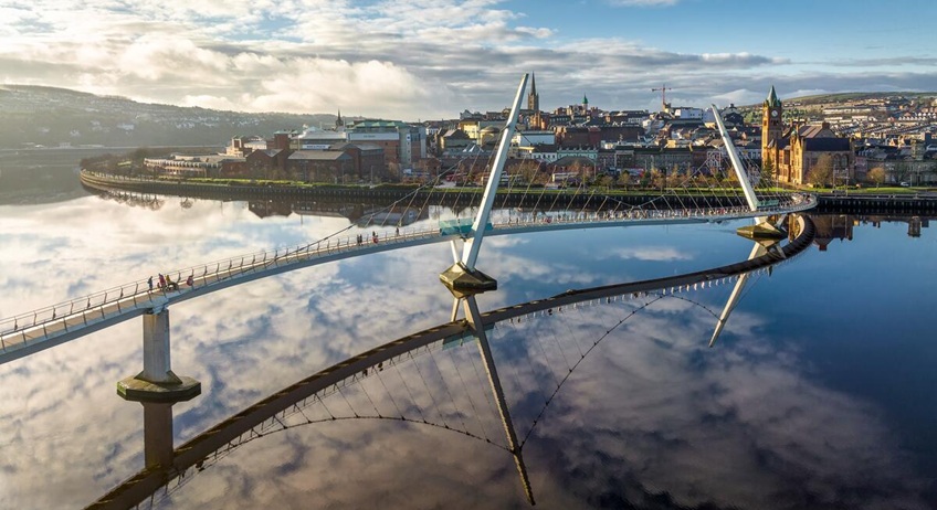 Bridge over a river leading into a cityscape.