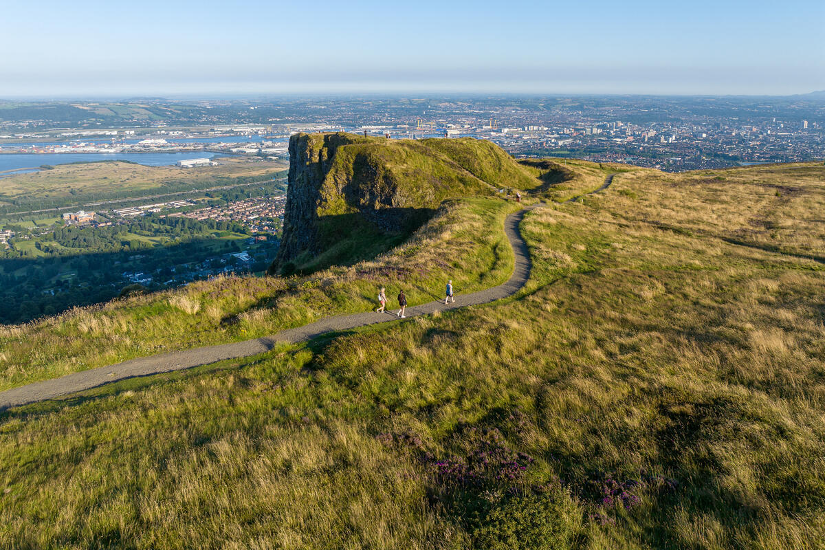 Cave Hill, Co. Antrim 3 people climbing a hill with a view of Belfast city behind