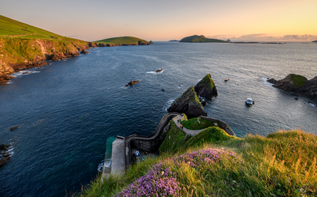 Blick auf den Pier von Dunquin bei Sonnenuntergang mit der dramatischen Küstenlandschaft